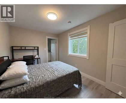 A bedroom with a bed, nightstand, and window.
