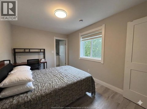 A bedroom with a bed, nightstand, and window.