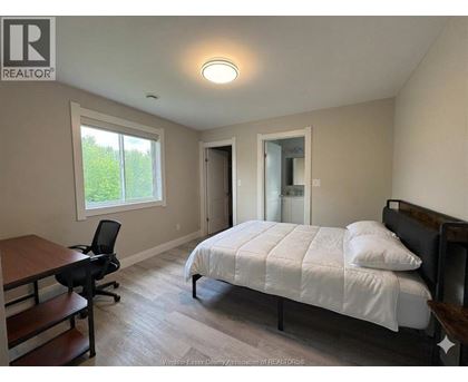 A bedroom with a bed, desk, and chair.