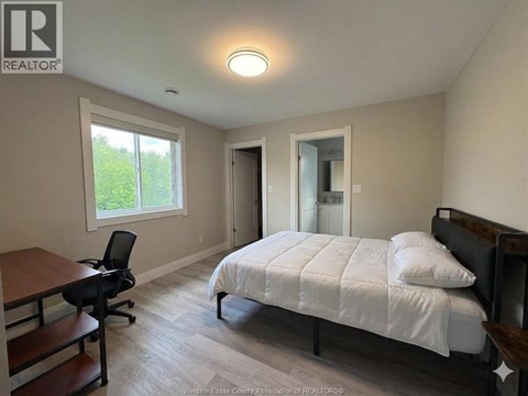 A bedroom with a bed, desk, and chair.