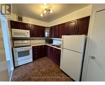 A kitchen with brown cabinets and white appliances.