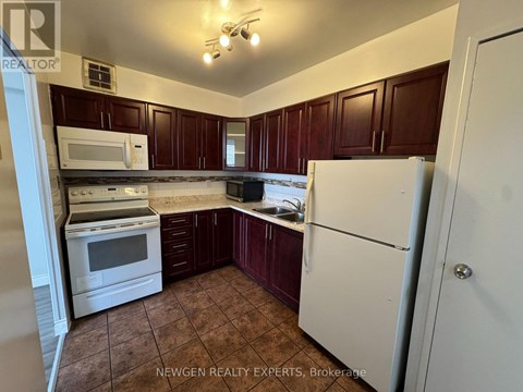 A kitchen with brown cabinets and white appliances.