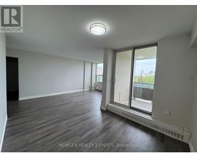A spacious room with wooden flooring and a sliding glass door leading to a balcony.