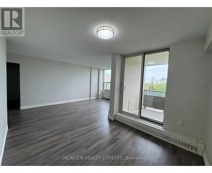 A spacious room with wooden flooring and a sliding glass door leading to a balcony.