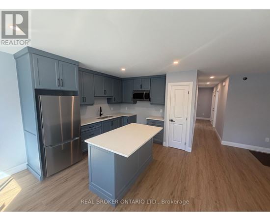 A kitchen with a refrigerator, cabinets, and a countertop.