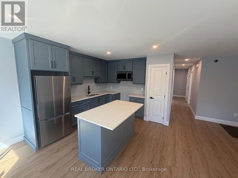 A kitchen with a refrigerator, cabinets, and a countertop.