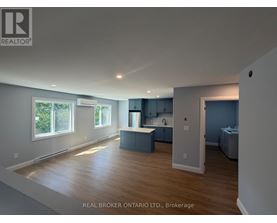 A spacious room with a kitchen area and a large window.