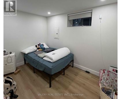 A bedroom with a bed, a window, and a wall-mounted air conditioner unit.