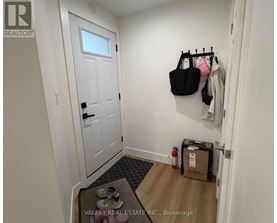 A hallway with a door, a coat rack, and a box on the floor.