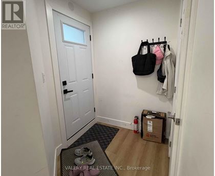 A hallway with a door, a coat rack, and a box on the floor.