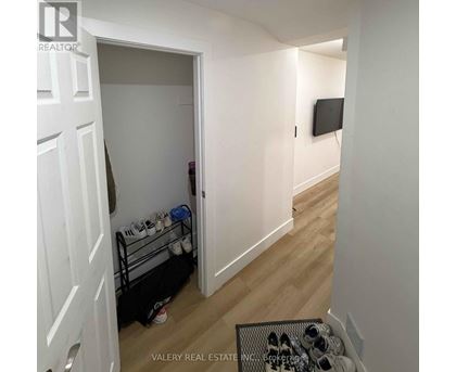A hallway with a doorway leading to a room with a TV on the wall.
