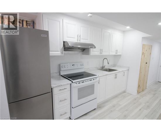 A modern kitchen with white cabinets and a stainless steel refrigerator.