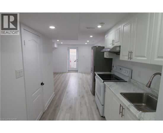 A kitchen with white cabinets and a black refrigerator.