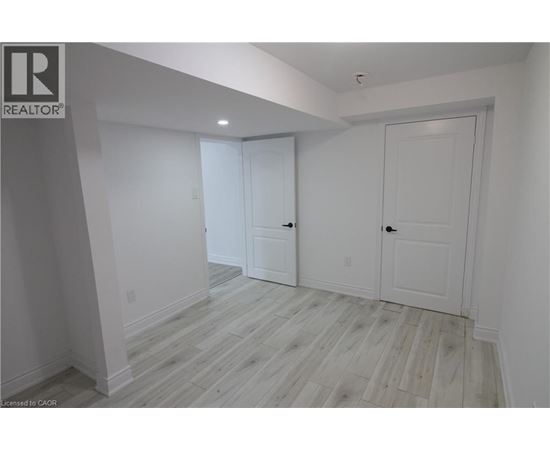 A white room with wood flooring and two doors.