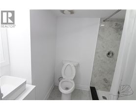 A white toilet in a small bathroom with a shower.