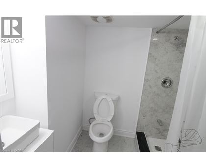 A white toilet in a small bathroom with a shower.