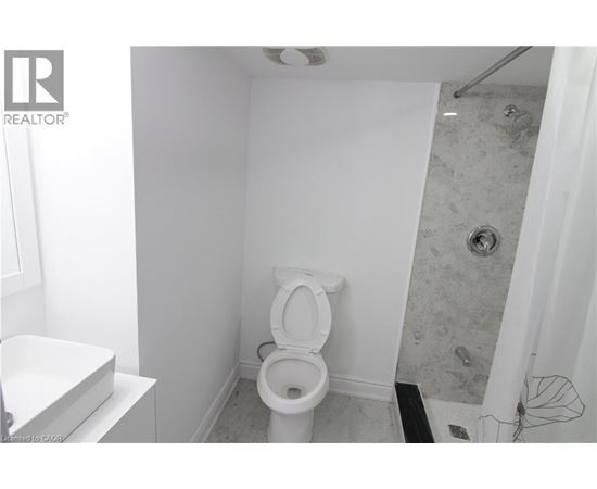 A white toilet in a small bathroom with a shower.