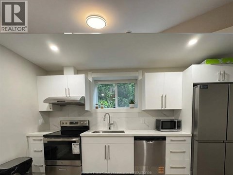 A white kitchen with a black stove top oven.