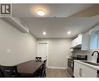 A kitchen with a table and chairs in the foreground and a stove top oven in the background.