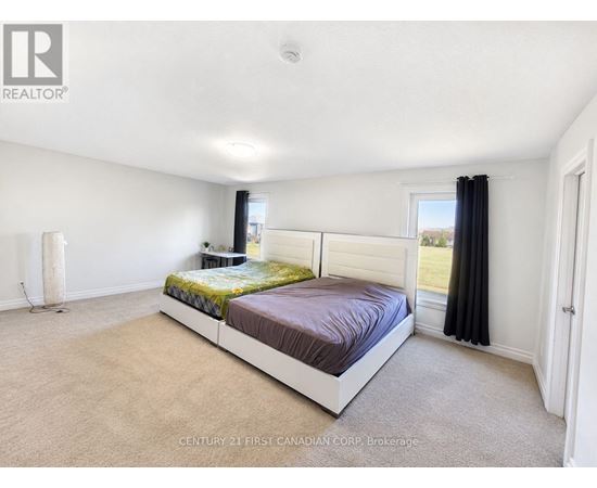A bedroom with a large bed and a window with black curtains.