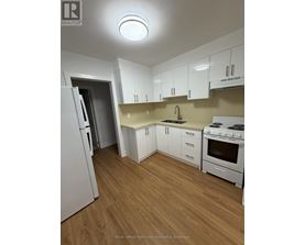 A kitchen with white appliances and wooden floors.