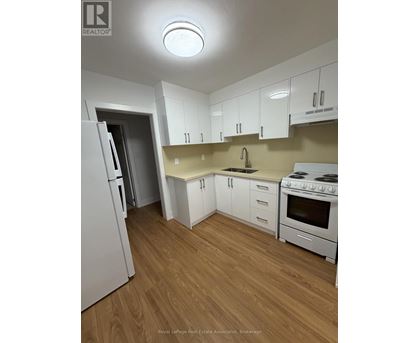 A kitchen with white appliances and wooden floors.