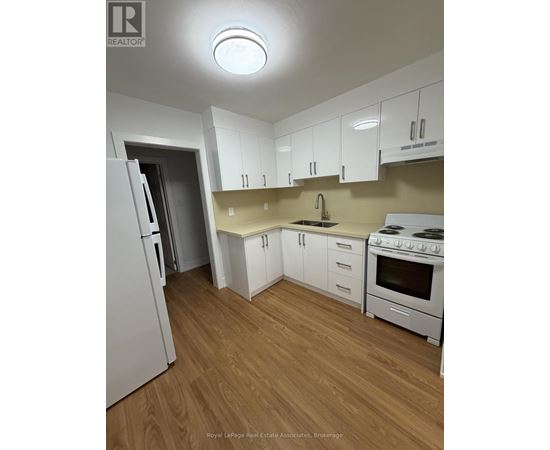 A kitchen with white appliances and wooden floors.
