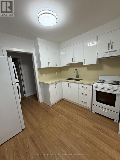 A kitchen with white appliances and wooden floors.