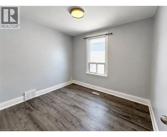 A room with a window and a wooden floor.