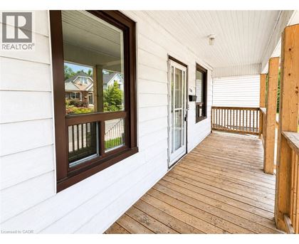A wooden deck with a white wall and a window.