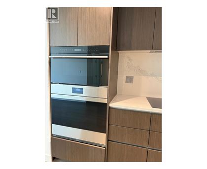 A modern kitchen with a stainless steel oven and wooden cabinets.