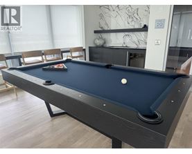 A pool table in a room with a marble wall and a fireplace.