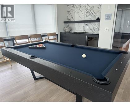 A pool table in a room with a marble wall and a fireplace.