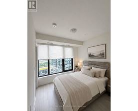 A bedroom with a large bed and a view of a cityscape through the window.