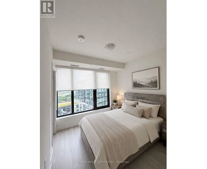 A bedroom with a large bed and a view of a cityscape through the window.