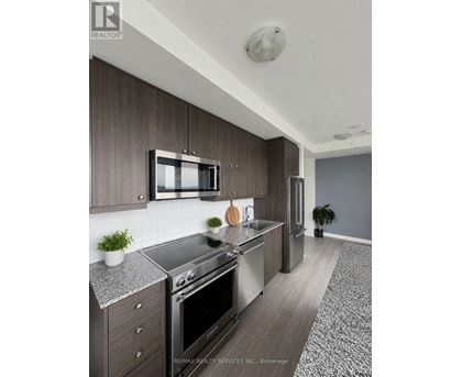 A modern kitchen with dark wood cabinets and stainless steel appliances.