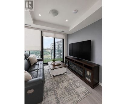 A modern living room with a black leather sofa and a flat screen TV.