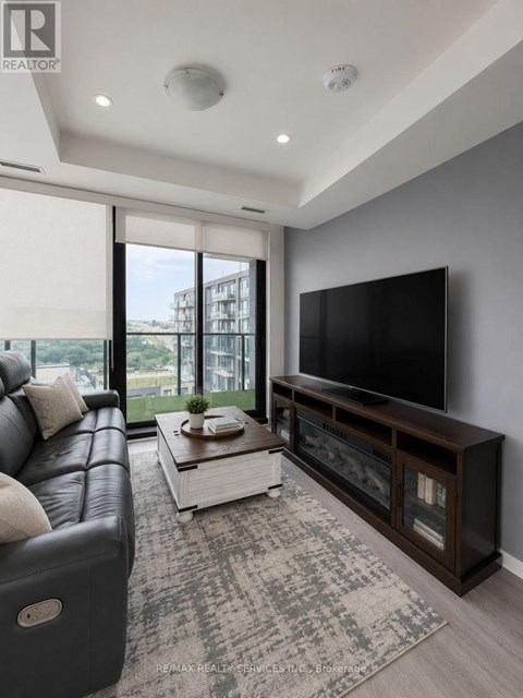 A modern living room with a black leather sofa and a flat screen TV.