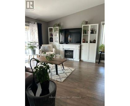 A living room with a fireplace, a white armchair, and a TV.