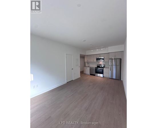 A spacious kitchen with stainless steel appliances and wooden flooring.