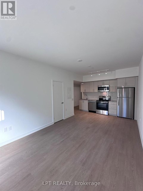 A spacious kitchen with stainless steel appliances and wooden flooring.