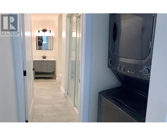 A modern kitchen with a stainless steel oven and a sink with a mirror above it.