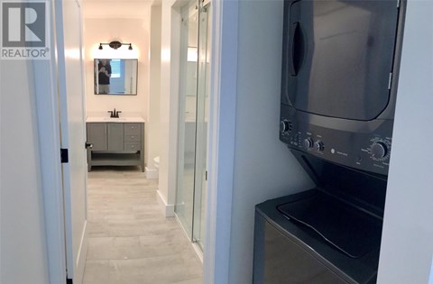 A modern kitchen with a stainless steel oven and a sink with a mirror above it.