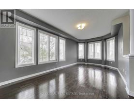 A spacious room with wooden floors and large windows.