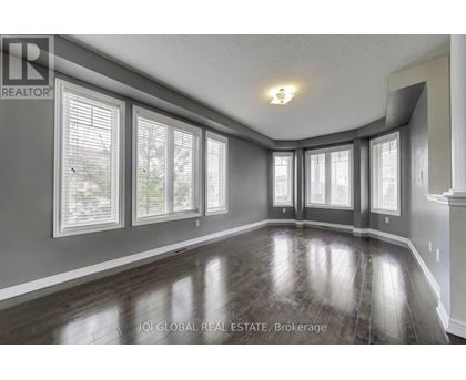 A spacious room with wooden floors and large windows.