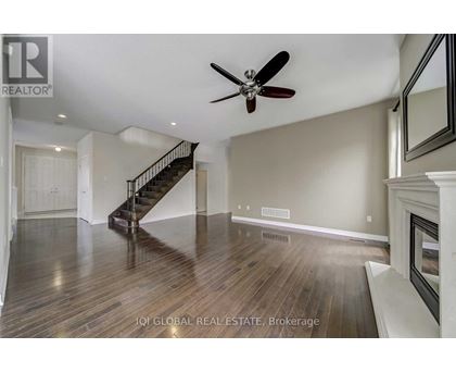 A spacious room with a staircase and a ceiling fan.