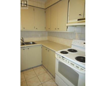 A kitchen with a stove, sink, and cabinets.