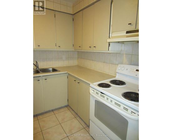 A kitchen with a stove, sink, and cabinets.