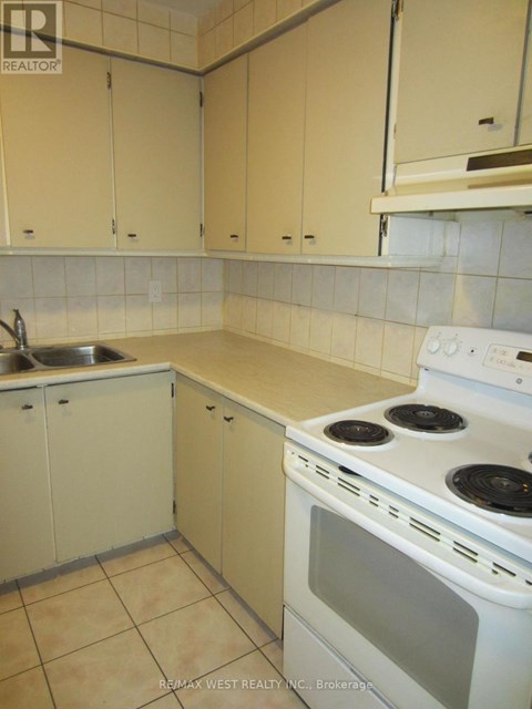 A kitchen with a stove, sink, and cabinets.