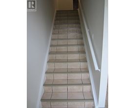 A staircase with beige tiles and white railings.
